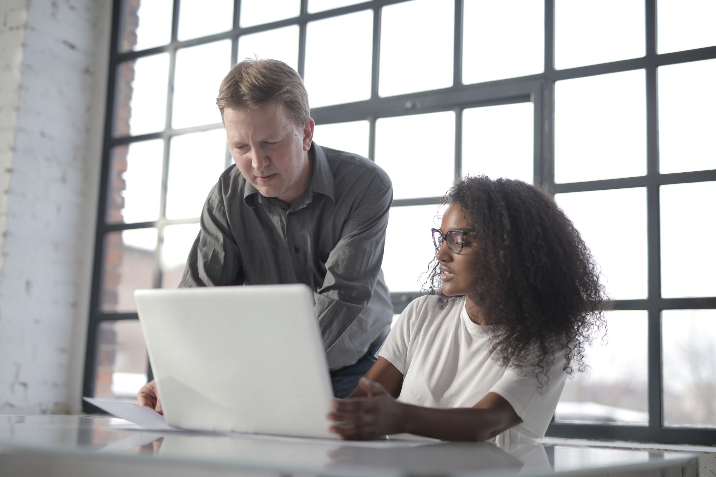 Black woman and colleague reviewing paperwork with laptop