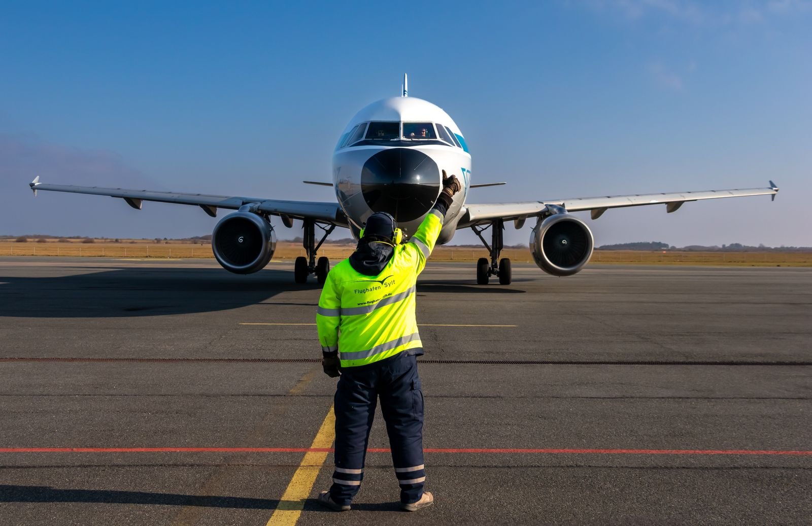 Airport ground worker guiding an aircraft on the apron