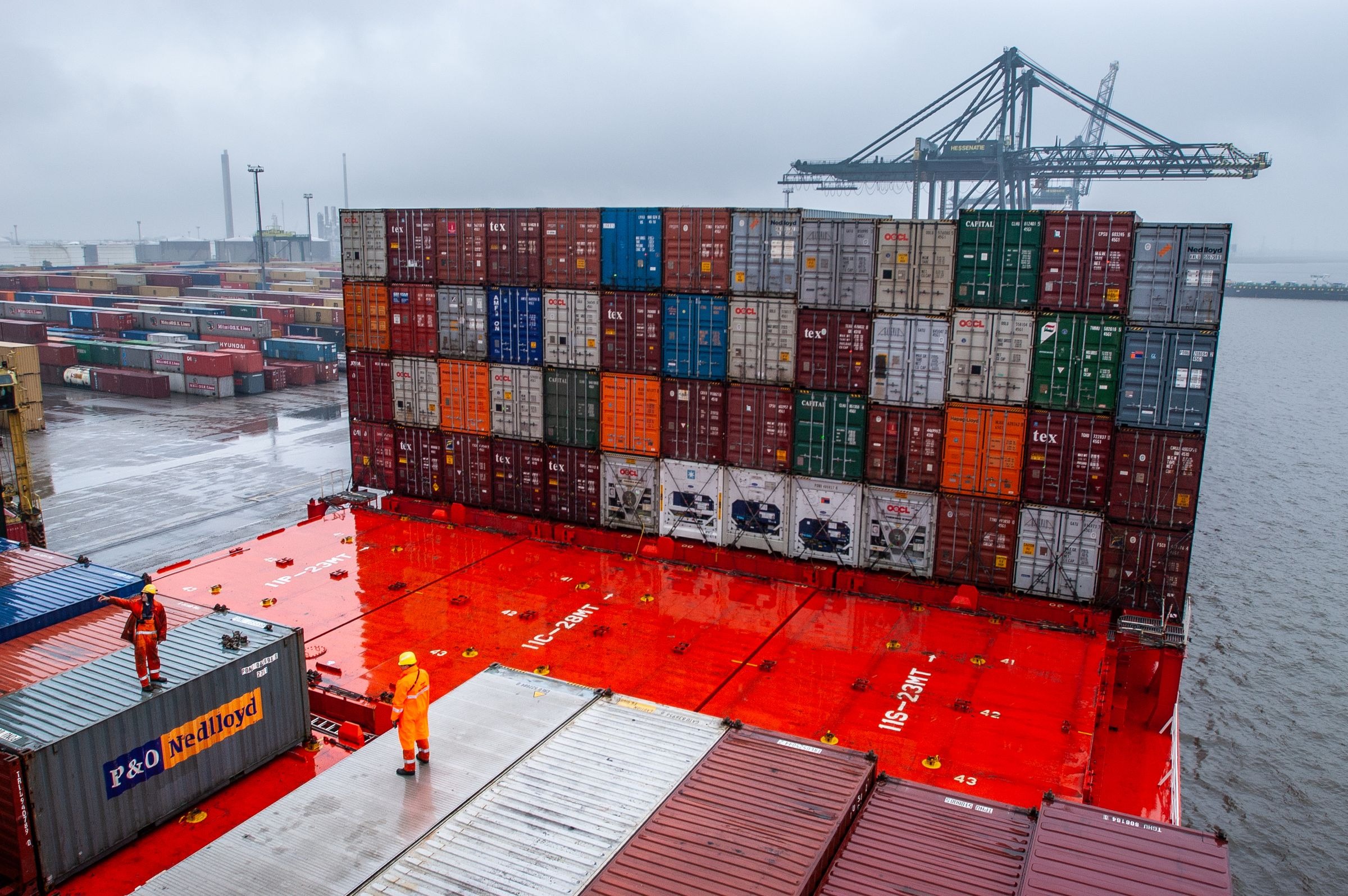 Real port workers and shipping containers on cargo ship deck