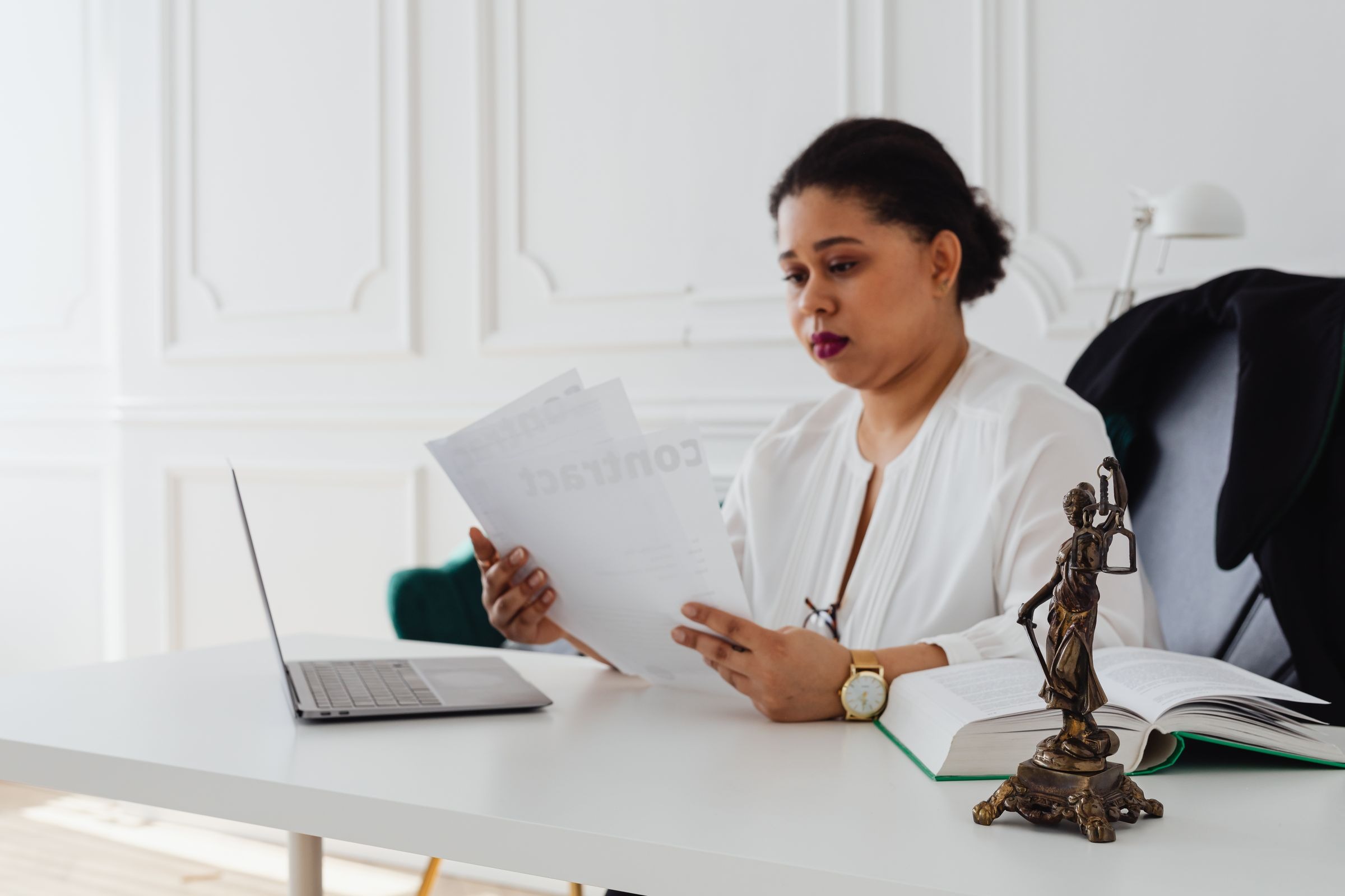 Black woman reviewing legal documents at an office desk