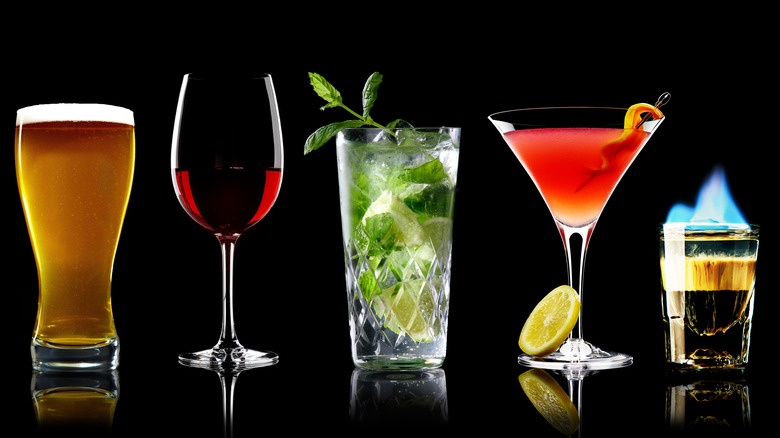Beer, wine and spirits in serving glasses against a black background