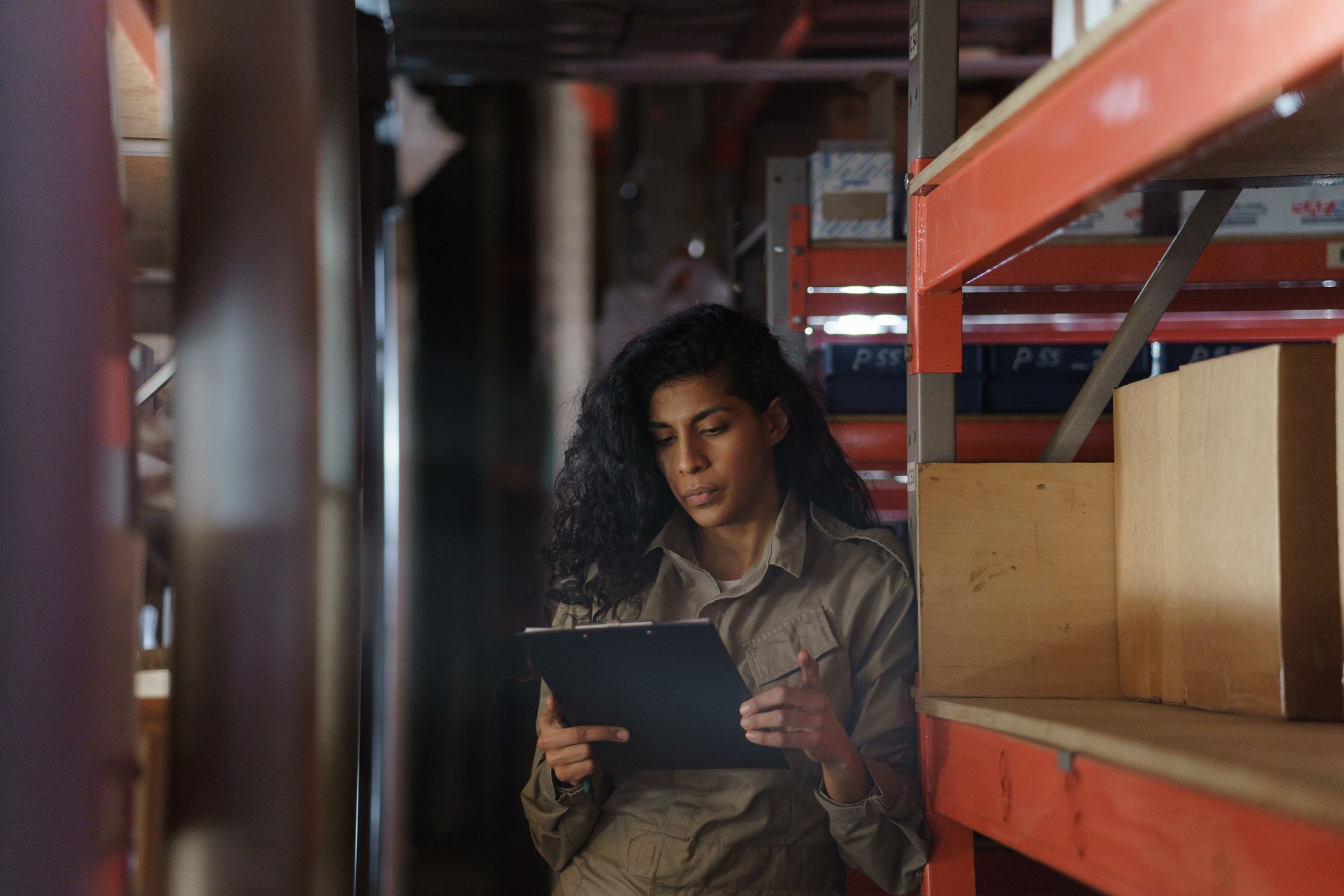 Woman inspecting warehouse inventory with a clipboard