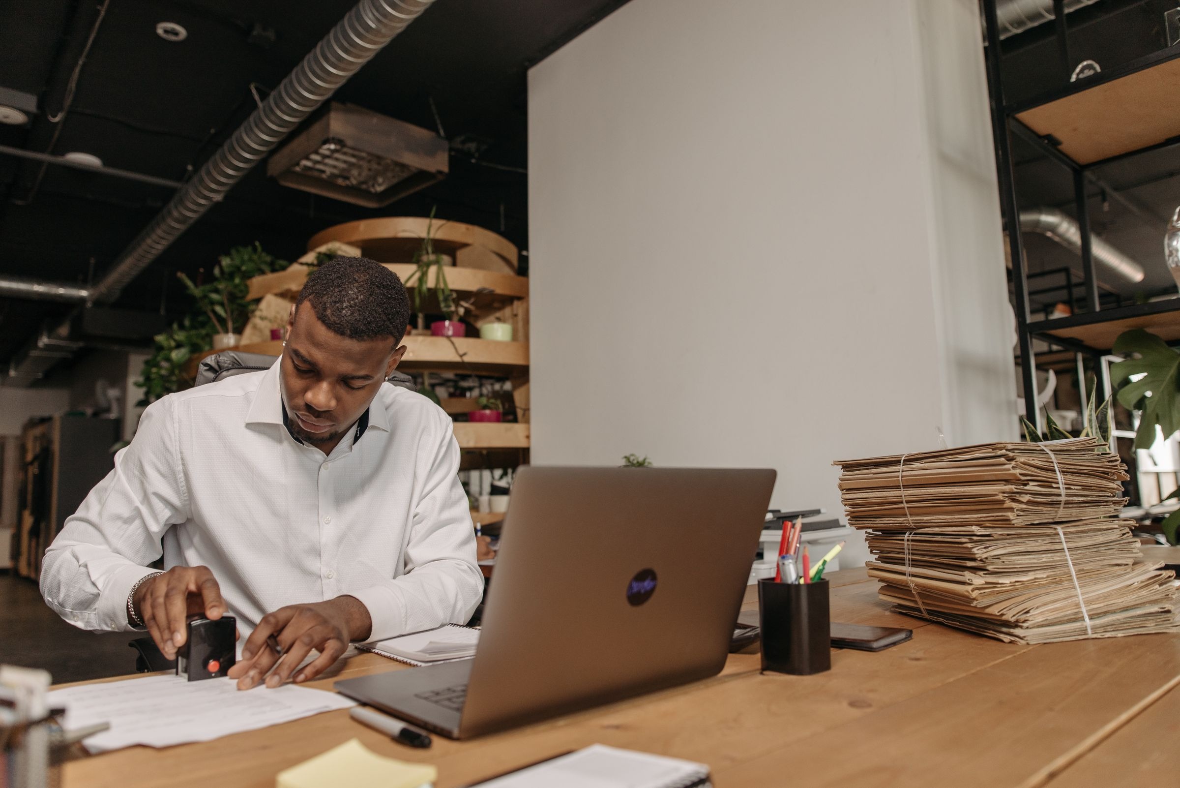 Man with short hair reviewing business paperwork beside a laptop