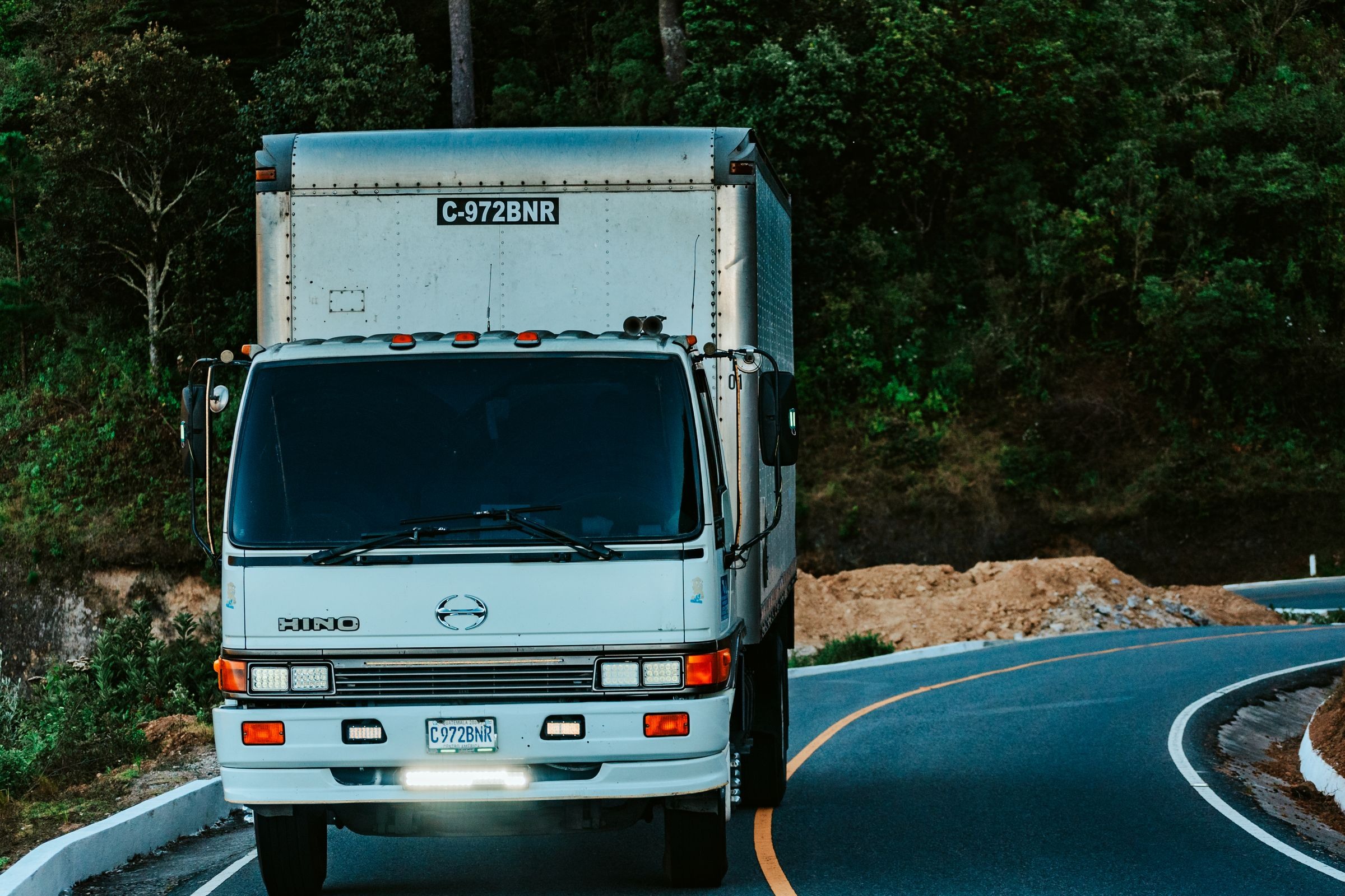 White cargo box truck driving on a forest road