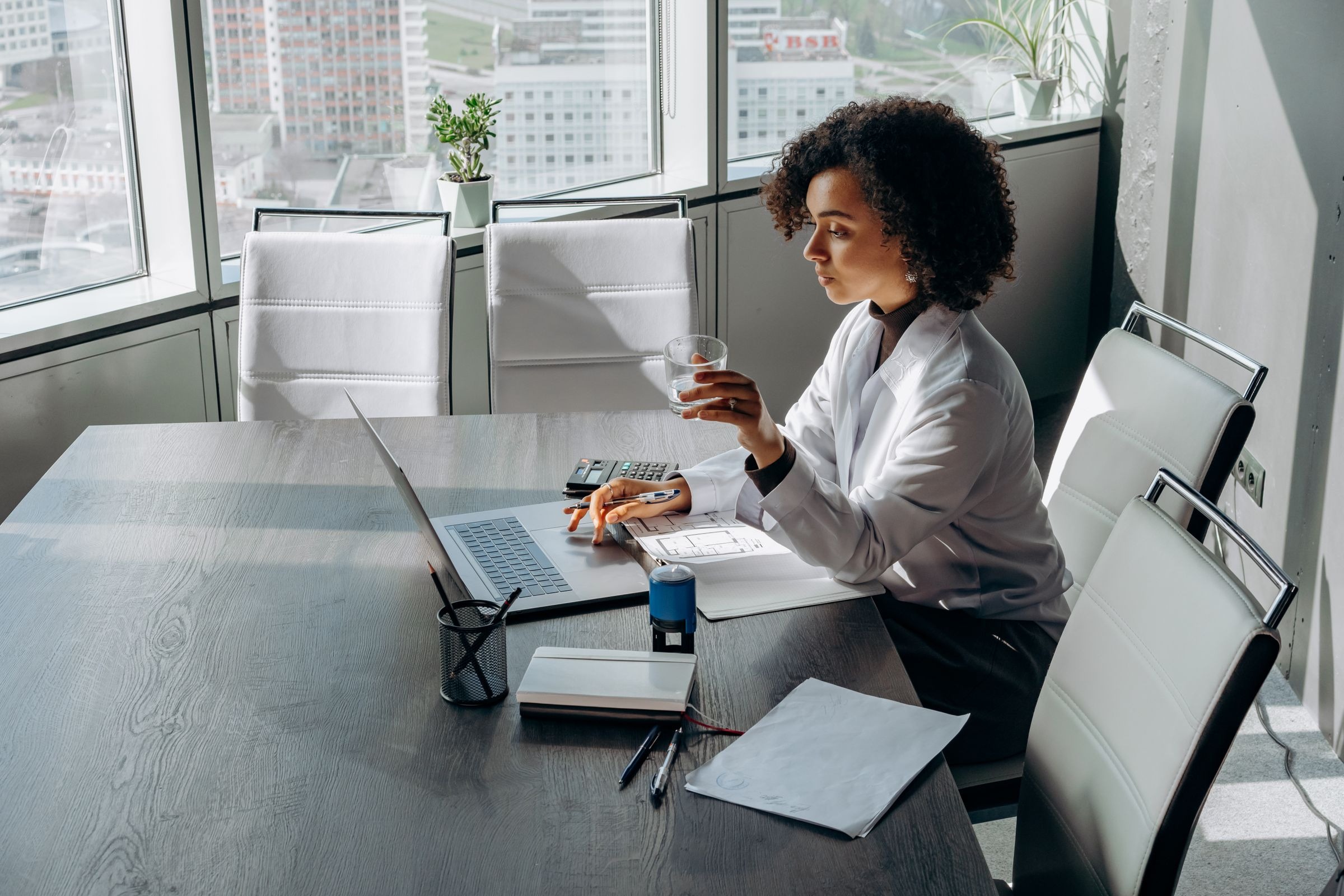 Black woman using laptop in bright office; generic electronic payment administration illustration